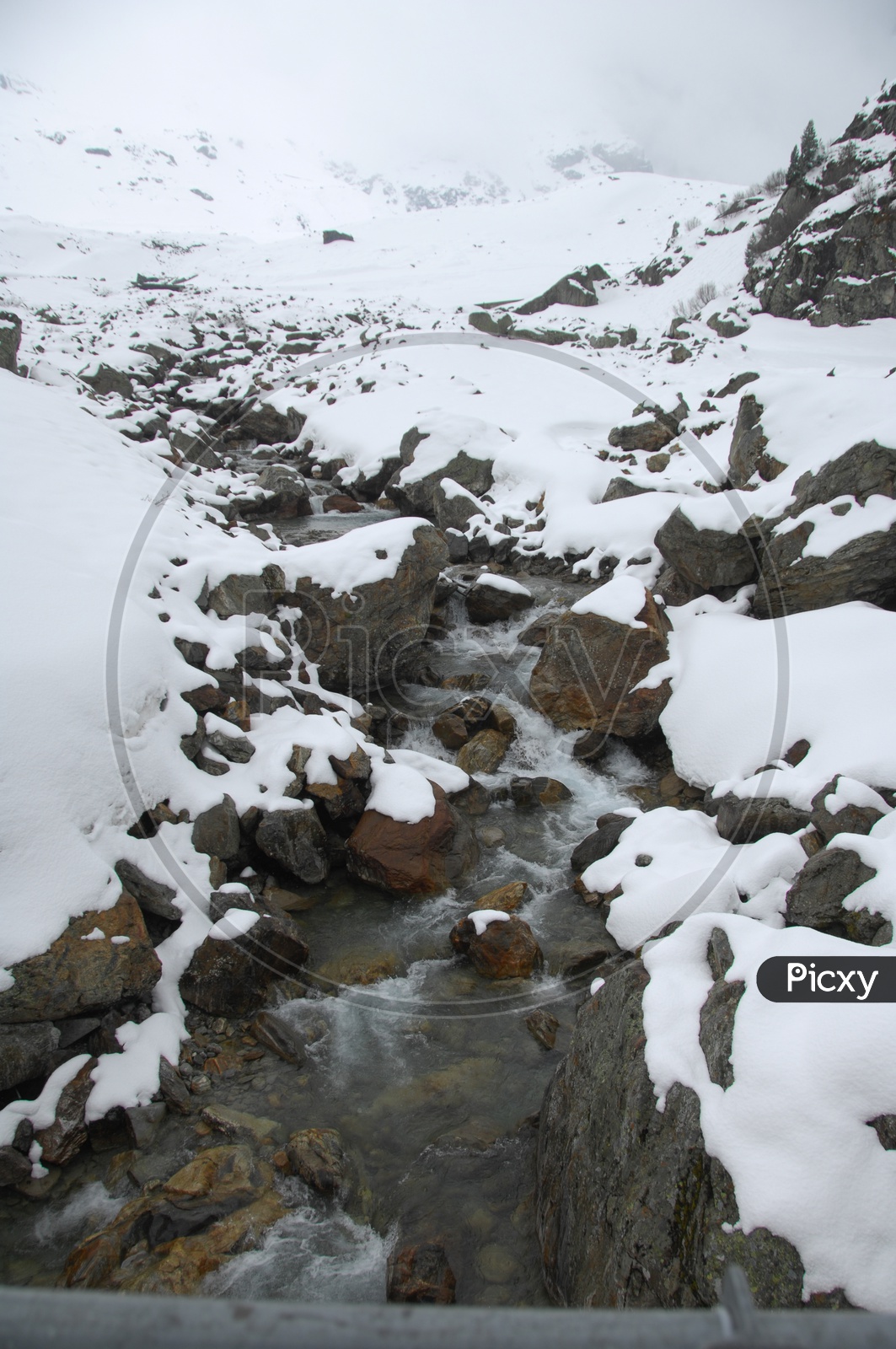 Water stream along the rocks covered with snow