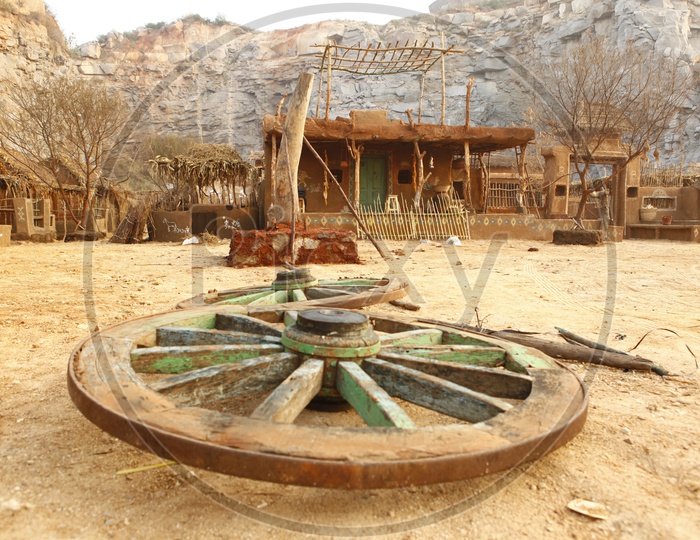 Wooden wheel on a road near thatched mud huts
