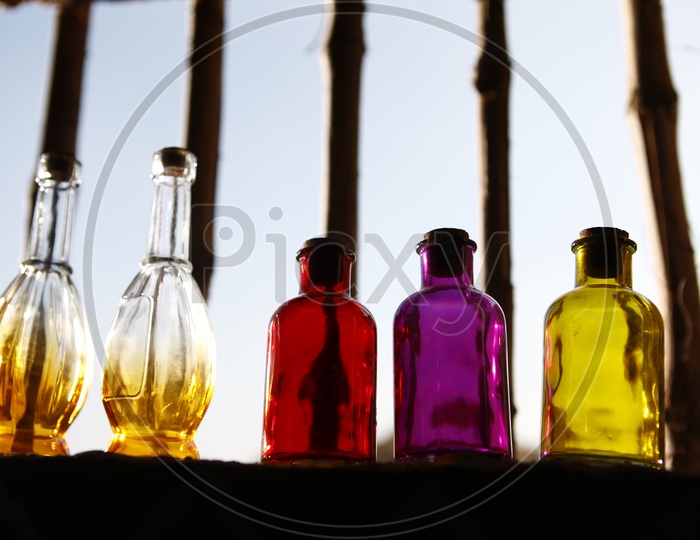 Colored glass bottles with a cork lid on a window sill