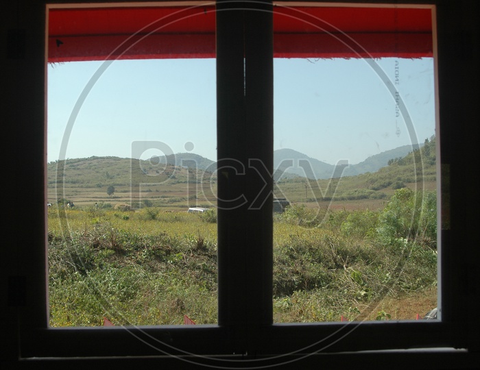 View of the fields in the valley through a glass window
