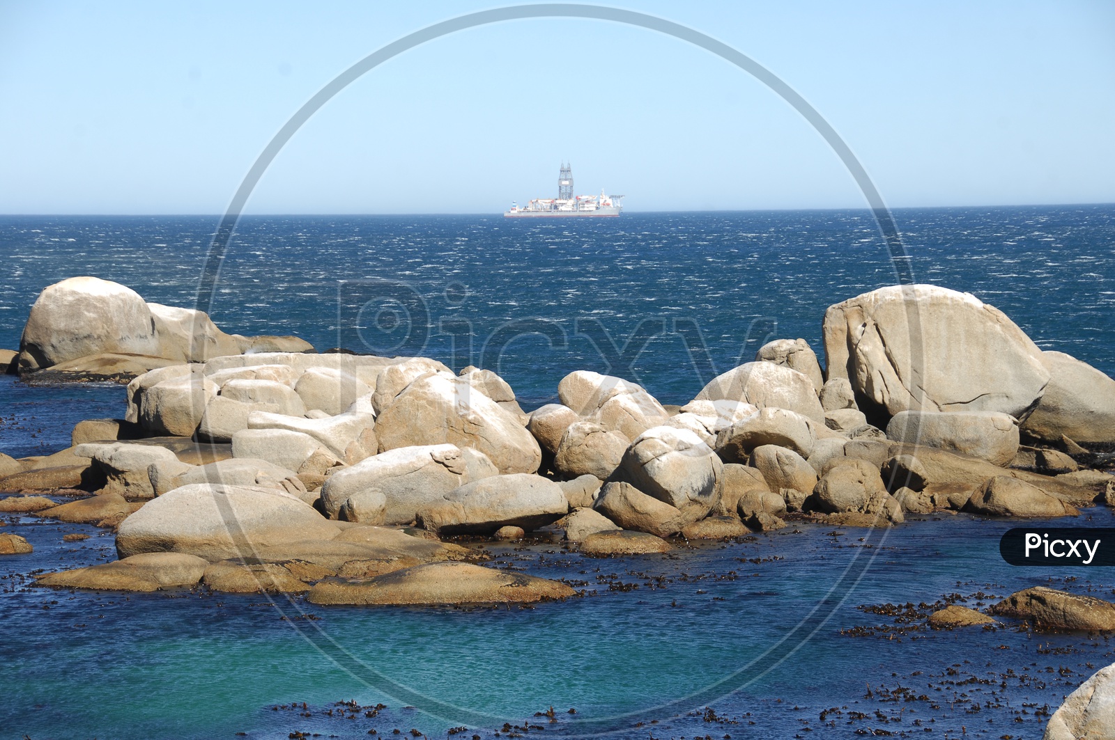 Rocks in the blue sea with a ship in the background