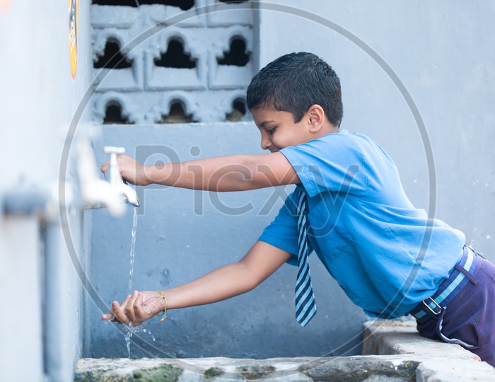 Primary government school student washing his hands at a hand wash station