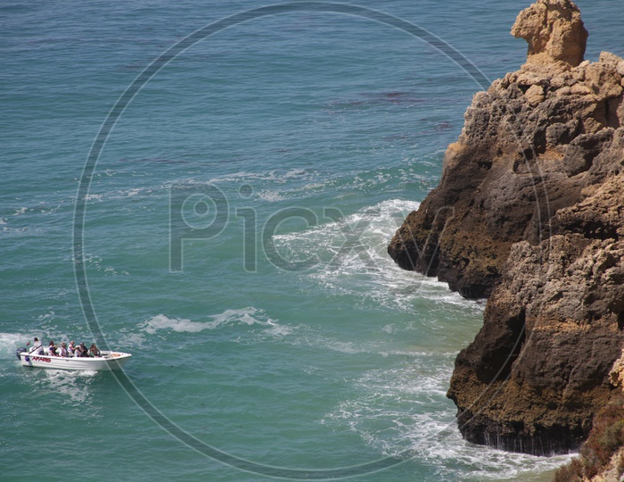 people moving in a boat beside a cliff