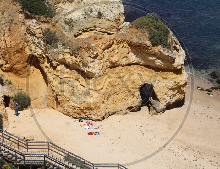 people taking sun bath beside a cliff in the beach