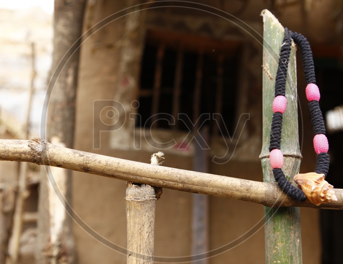 Black thread chain with Conch shell locket hanged on bamboo fencing