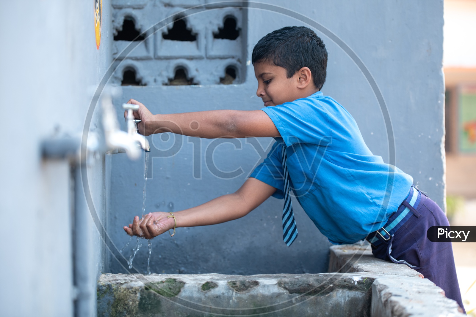 Primary government school student washing his hands at a hand wash station