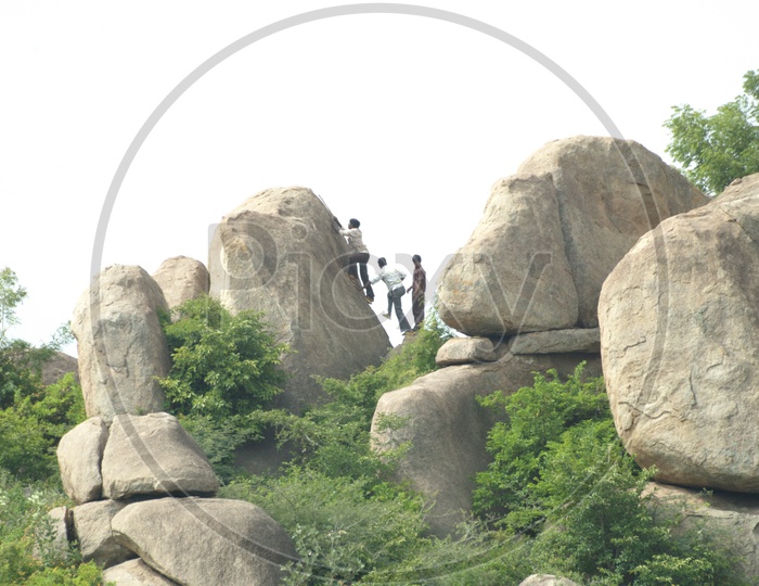Young men climbing onto a boulder