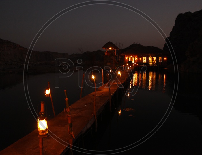 Lights on a wooden bridge over a pond during night