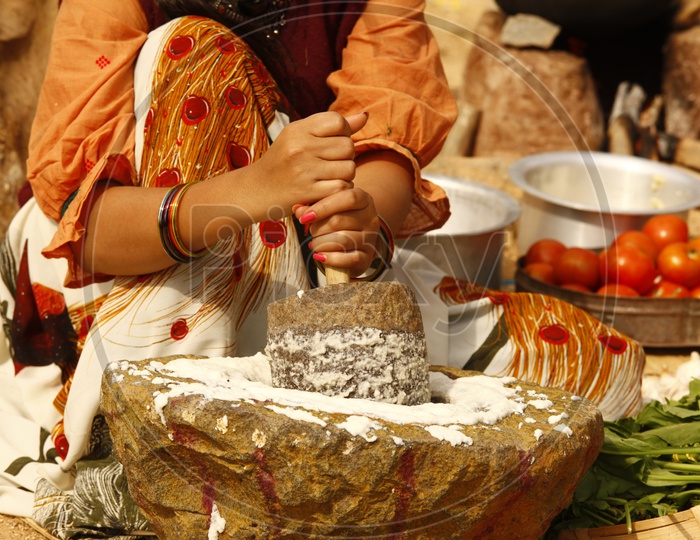 Image of An Indian woman grinding a batter in a traditional wet