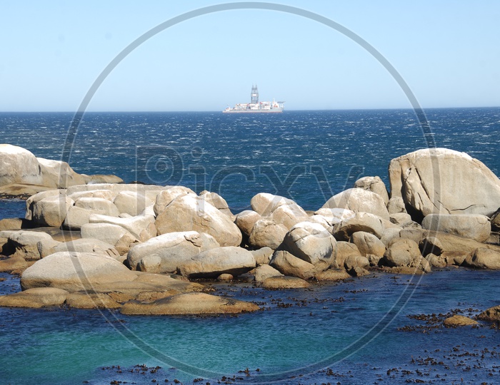 Rocks in the blue sea with a ship in the background