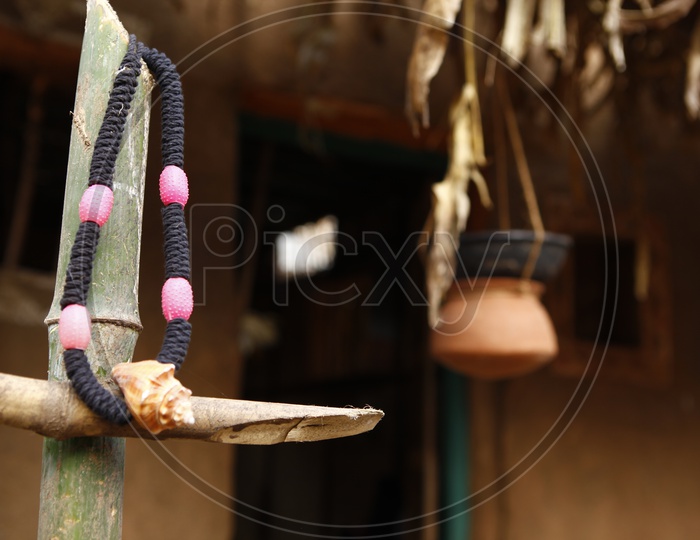 Black thread chain with Conch shell locket hanged on bamboo fencing