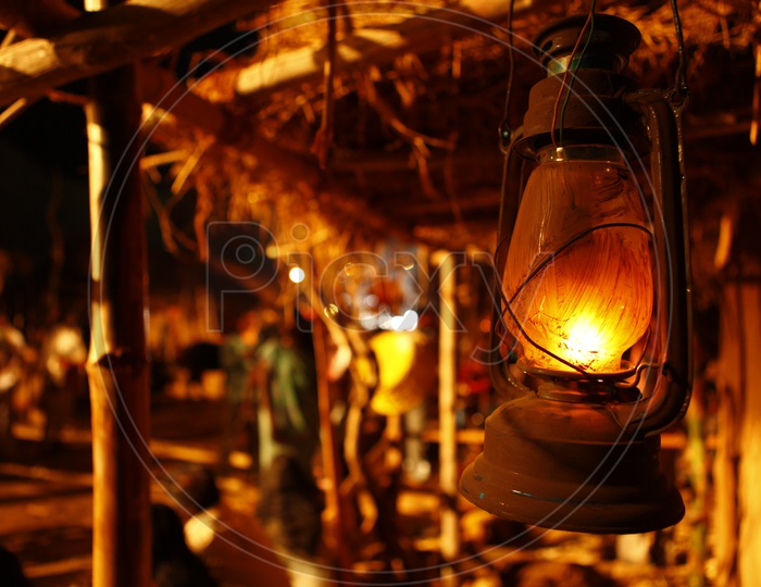 A lit lantern at a thatched mud hut