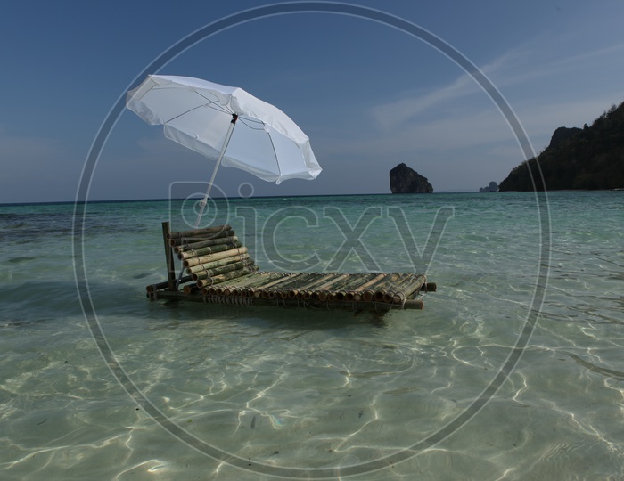 Bamboo pool chair with a white umbrella in the beach
