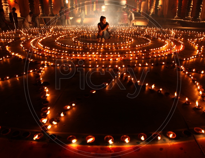 A woman sitting in the middle of clay lit diyas