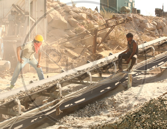 Men at work near the conveyor belt of the stone crusher