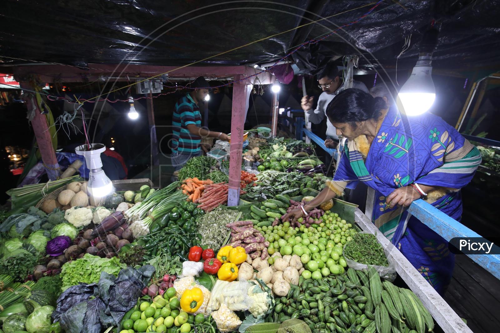 people shopping for vegetables under LED lights