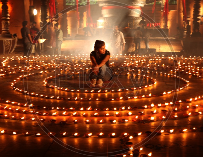 A woman sitting in the middle of Clay lit diyas