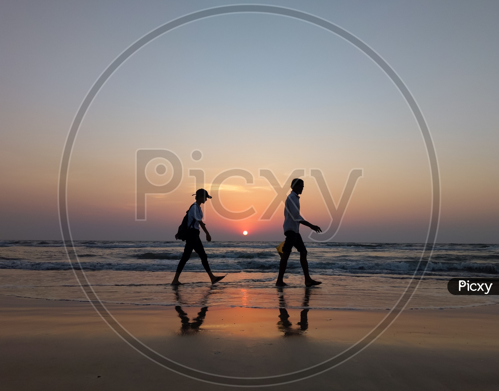 Silhouette Of Man Walking In a Beach With Sunset Sky In the Background