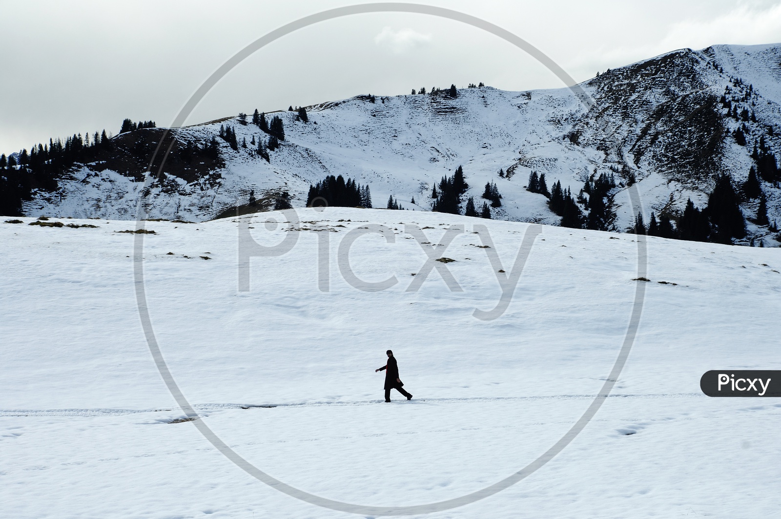 A Man Walking Alone in Snow Capped Mountains