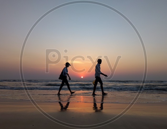 Silhouette Of Man Walking In a Beach With Sunset Sky In the Background