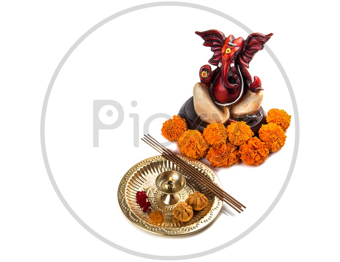 Lord Ganesh Idol with flowers and lightened up diya on white background