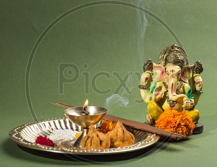Lord Ganesh Idol with flower and lightened up diya on white background