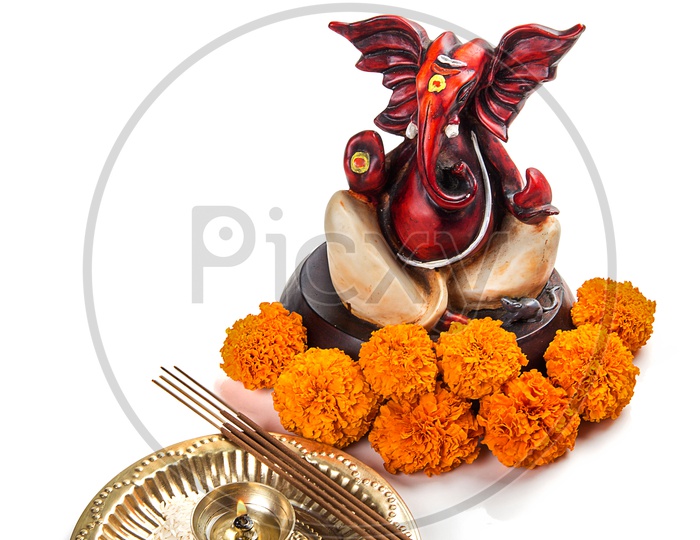Lord Ganesh Idol with flowers and diya on white background