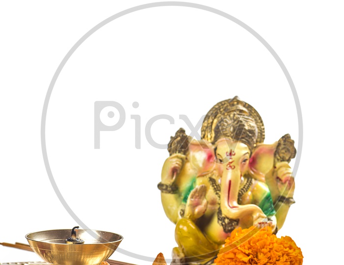 Lord Ganesh Idol with flowers and lightened up diya on white background