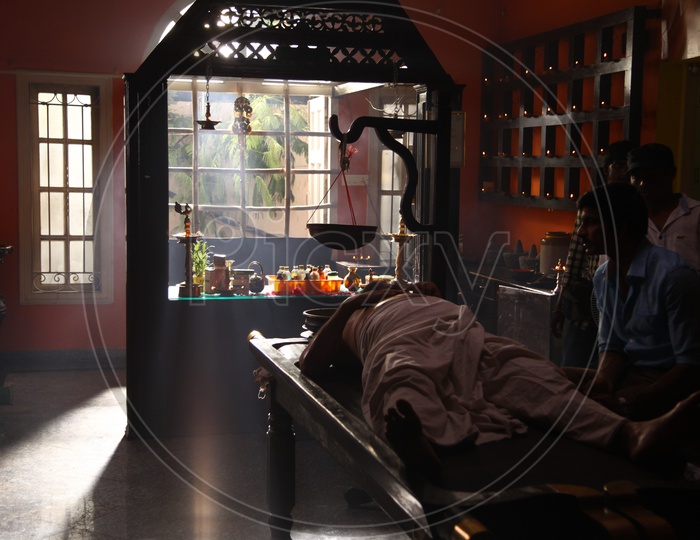 A man laying on bed having Ayurvedic treatment