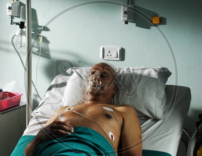 An old patient in a hospital bed with oxygen mask and saline