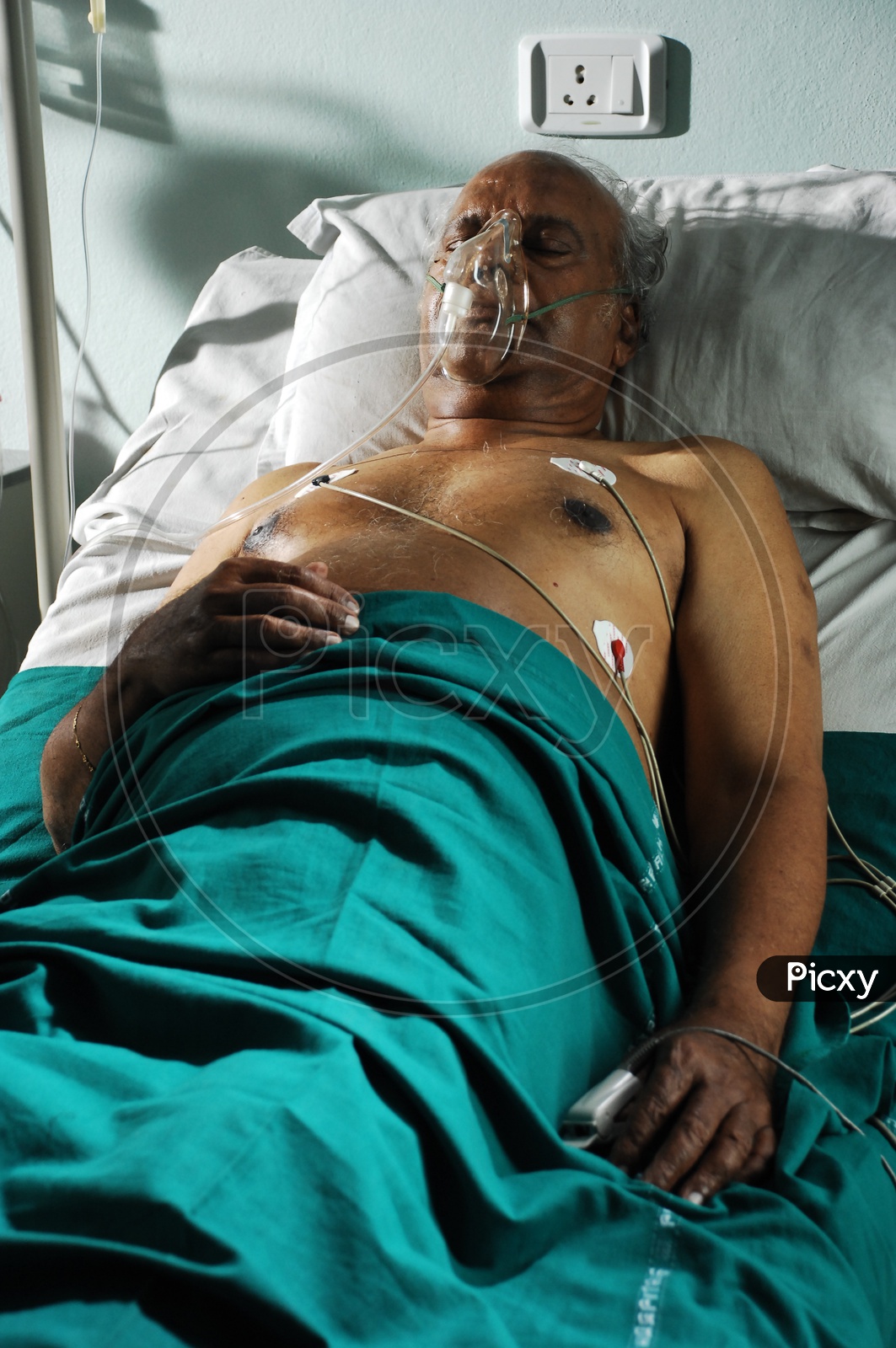 An old man in a hospital bed with oxygen mask