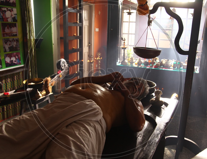 A man laying on bed having Ayurvedic treatment