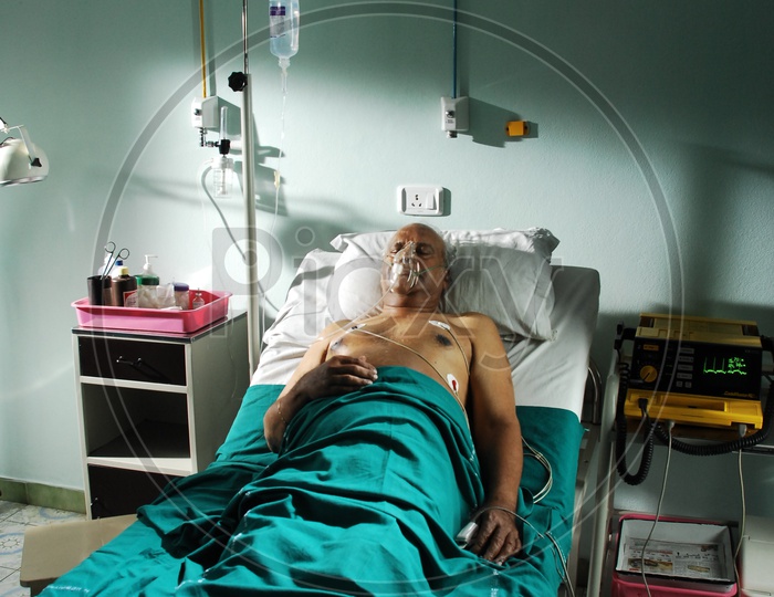 An old man in a hospital bed with oxygen mask and saline