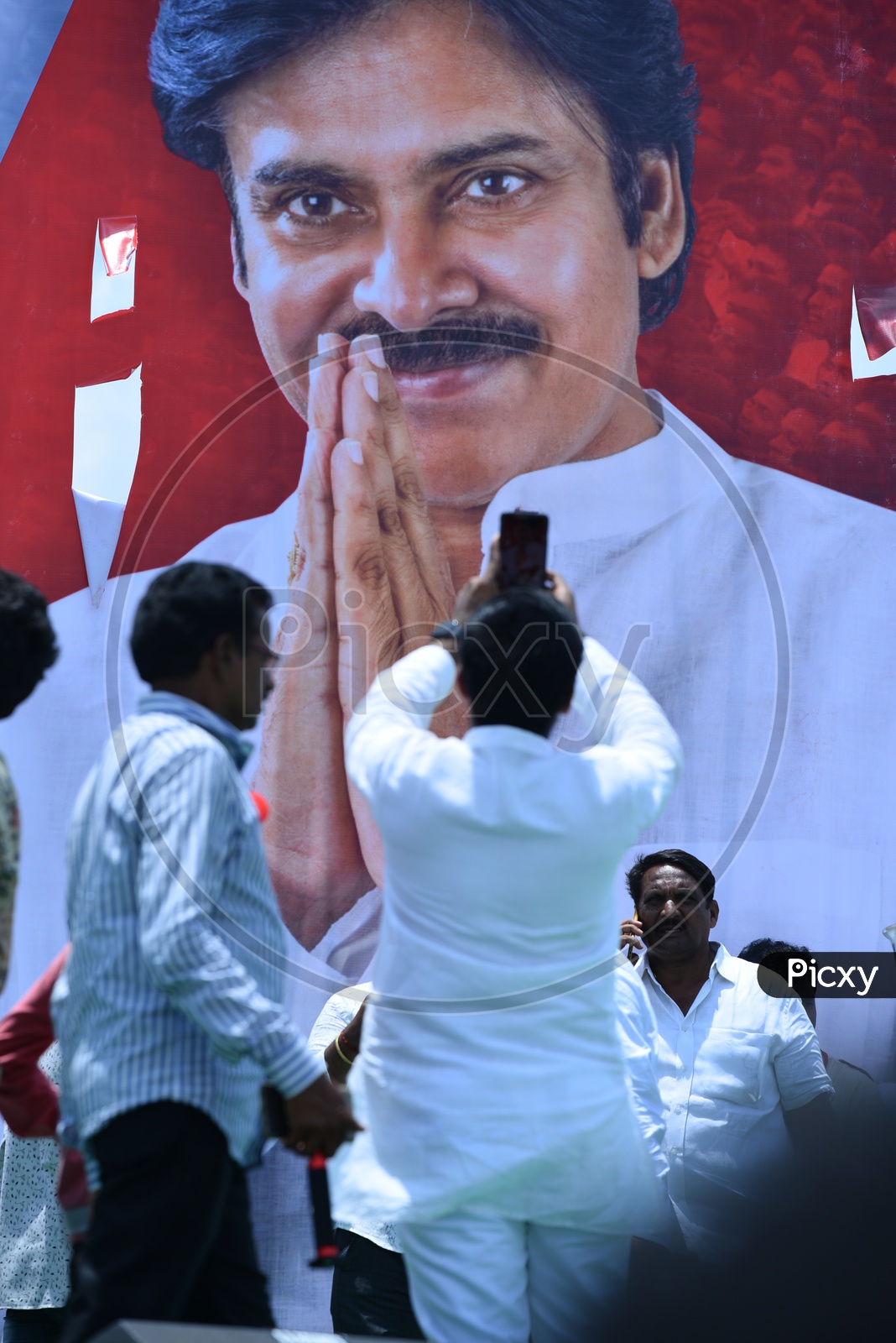 Jana sena party supporter taking the picture of Pawan Kalyan banner at an election campaign