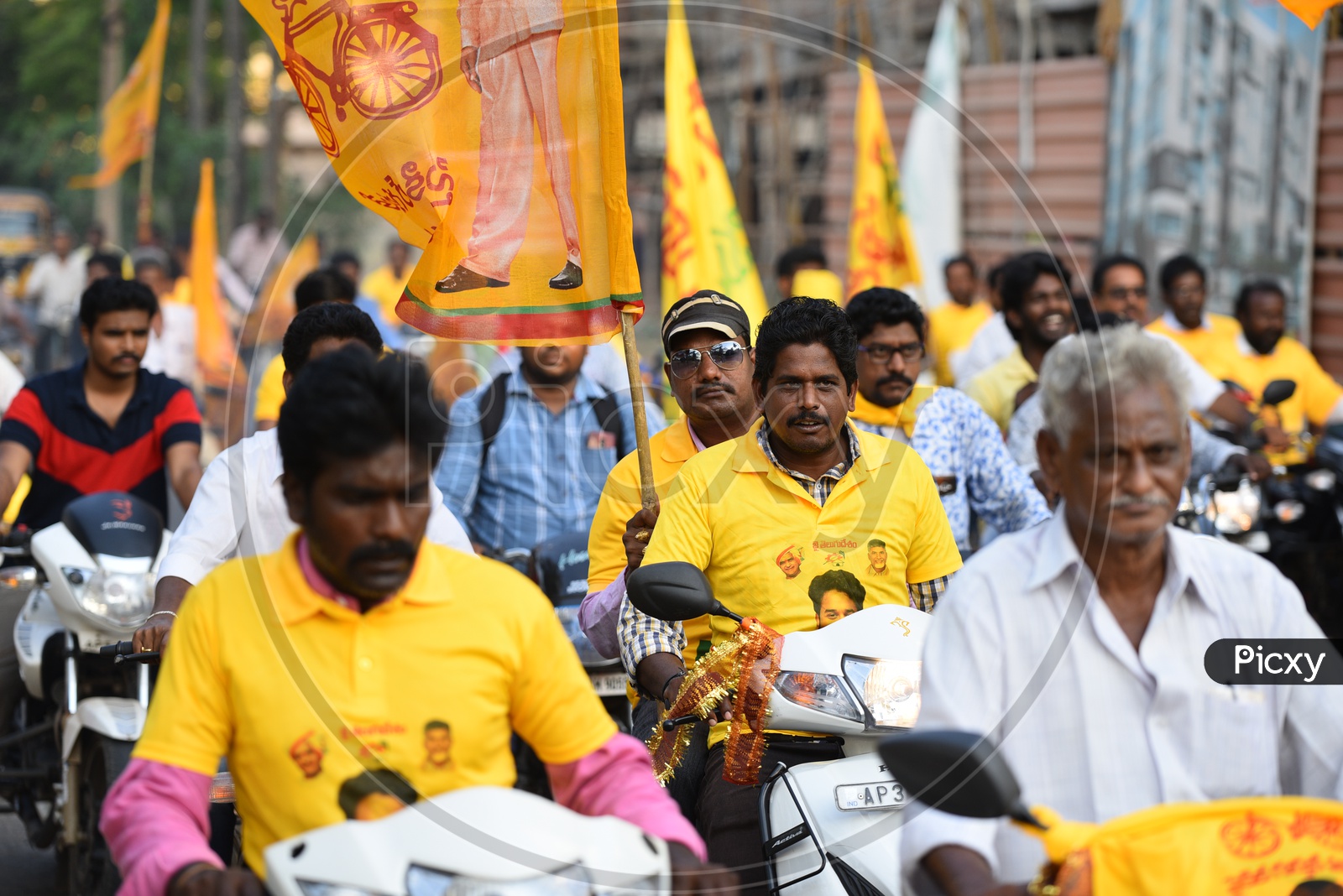 TDP party supporters wearing party t-shirts and riding bikes during an election campaign rally in Amalapuram