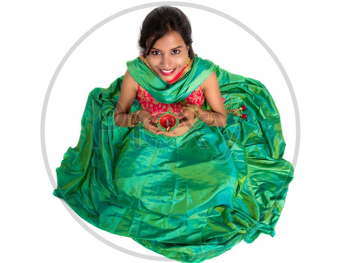 Portrait of a Young Indian Traditional Girl Sitting on Floor  With His Frock  wide Spread  and  Holding  Festival Dia  in Hand