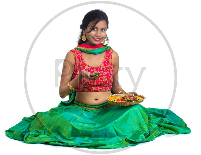 Portrait Of a Young Indian Traditional Woman Holding  Festival Dia  Plates  In Hand  Over a White Background