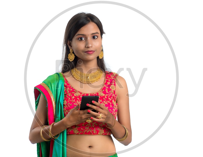 Portrait Of a Happy Young Indian Traditional Woman Holding a Smart Phone in Hand Over a Isolated White Background