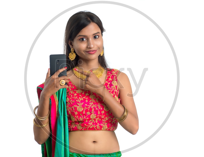 Portrait of a Young Traditional Indian  Woman  Showing Mobile  With an Expression and  a Gesture  over a White Isolated Background