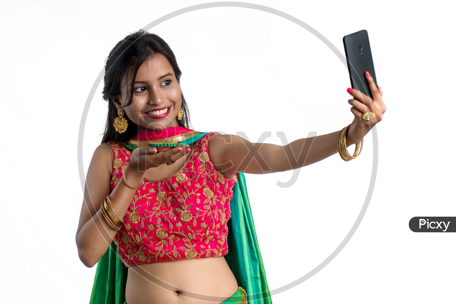 Portrait Of a Young Indian Traditional Girl Holding Festival Dia In Hand And Taking Selfie  in Smart Phone  Over a White Background