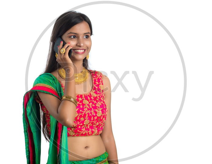 Portrait of a Happy Young  Traditional Indian Woman  Speaking In Smart Phone  Over a White  Background