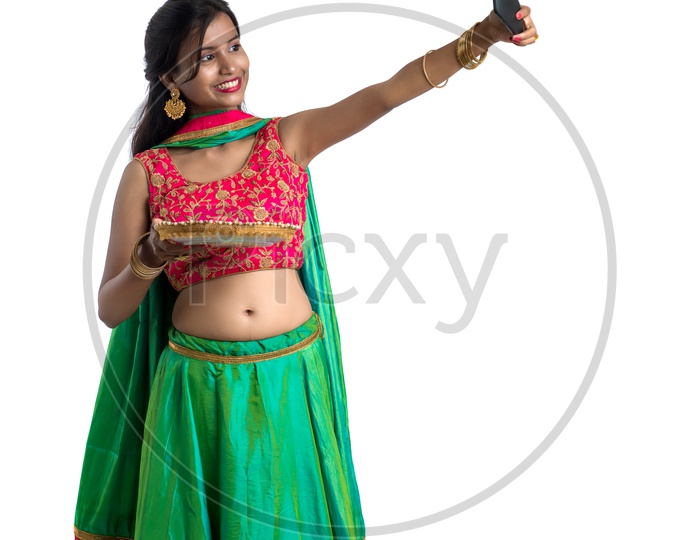 Portrait of a Young Indian Traditional Girl  Holding  Dia Plate And  Dia In Hand  and Taking  Selfie Over an Isolated White Background
