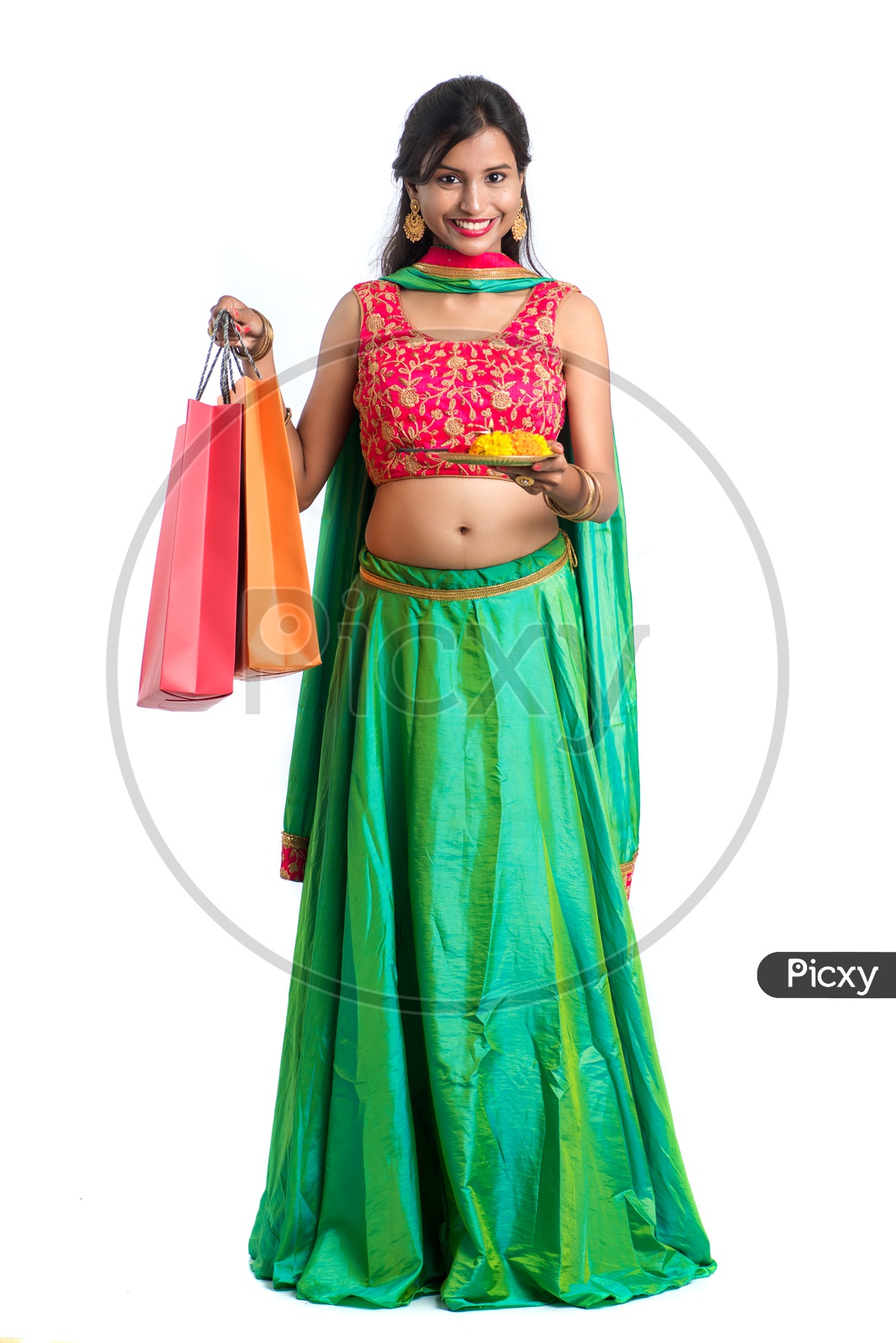 Portrait Of a Young India Traditional Woman  Holding Pooja Plate Or Dia  and Shopping Bags  in Hand  Over a White  Background
