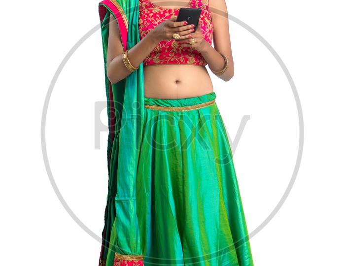 Portrait Of a Young Indian  Traditional Woman Looking  at  Smart Phone  With an Expression  And Gesture Over a  White Background