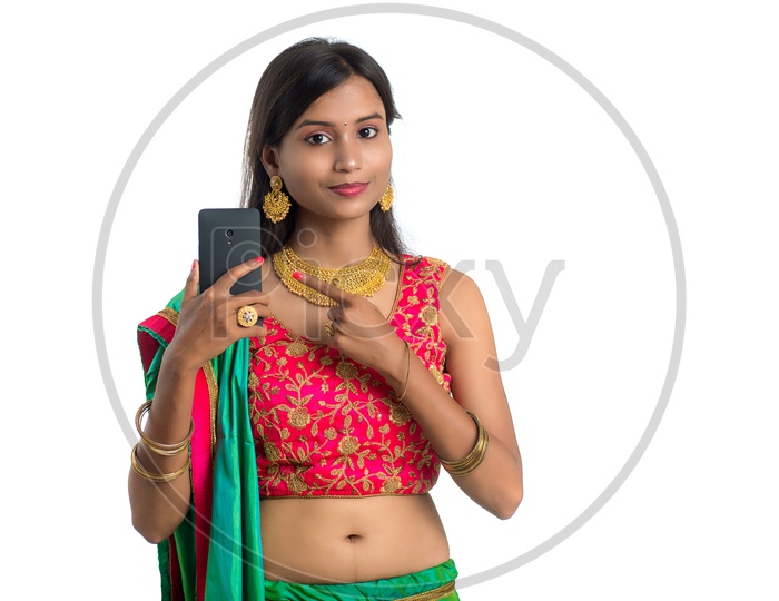 Portrait of a Young Traditional Indian  Woman  Showing Mobile  With an Expression and  a Gesture  over a White Isolated Background