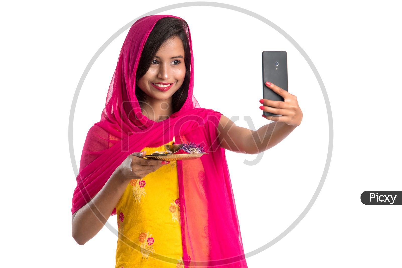 Beautiful Indian Girl Holding Pooja Thali Or Pooja Plate  In Hand and Taking Selfie with Smart Phone