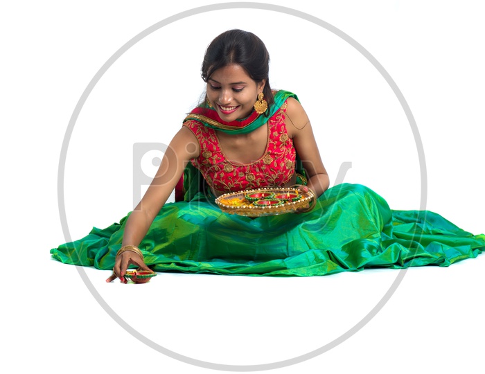 Portrait of a Young Traditional Indian Girl With Festival Dia And  Making Rangoli  Over a Isolated white Background