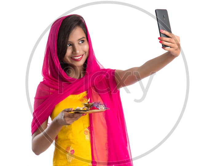 Beautiful Indian Girl Holding Pooja Thali Or Pooja Plate  In Hand and Taking Selfie With a Smart Phone