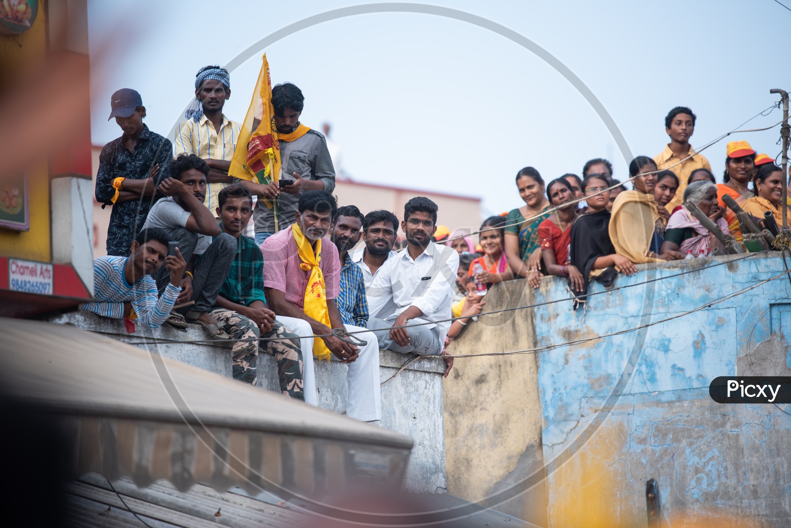 TDP Party Supporters Sitting On a Building Pit Wall and  Listening Curiously to Speech