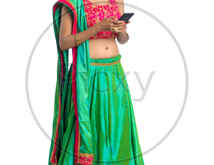 Portrait Of a Young Indian  Traditional Woman Looking  at  Smart Phone  With an Expression  And Gesture Over a  White Background